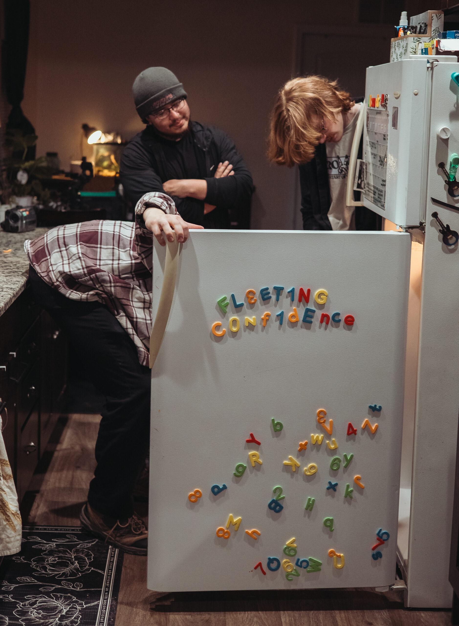 fleeting confidence looks into a fridge with their name spelled out in magnets on the door